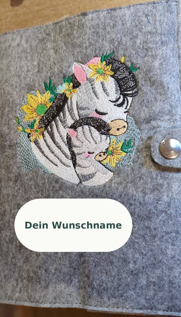 Gesundheitsheft-Hülle aus grauem Filz mit gesticktem Zebra-Motiv – Beispiel aus der Werkstatt